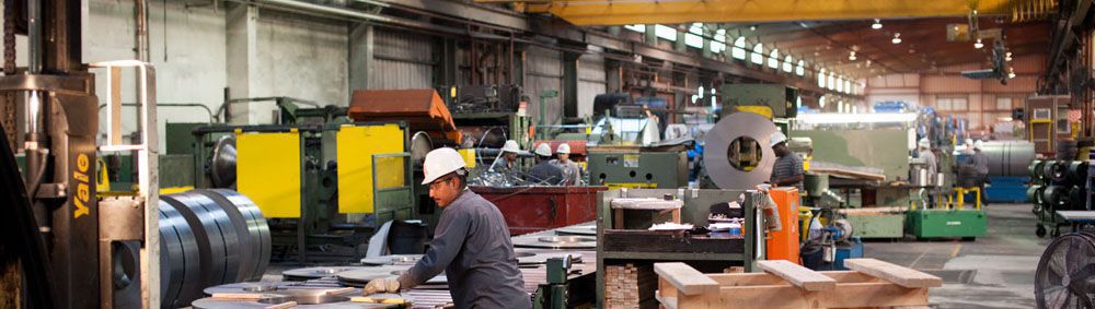 panoramic photo of two workers in hard hats surrounded by equipment working in the steel service center in California
